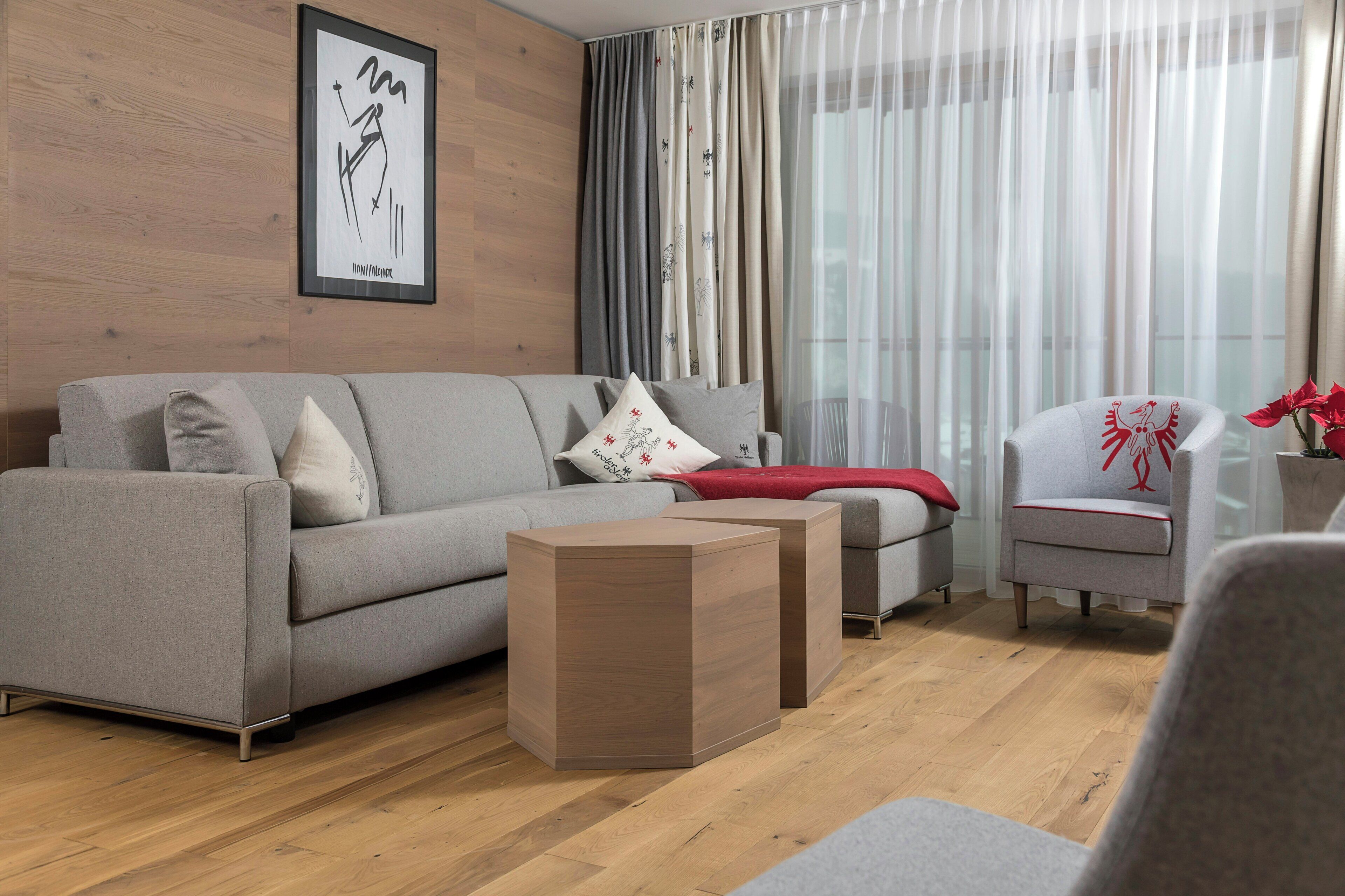 A modern living room with a grey sofa, a wooden coffee table, and a grey armchair.