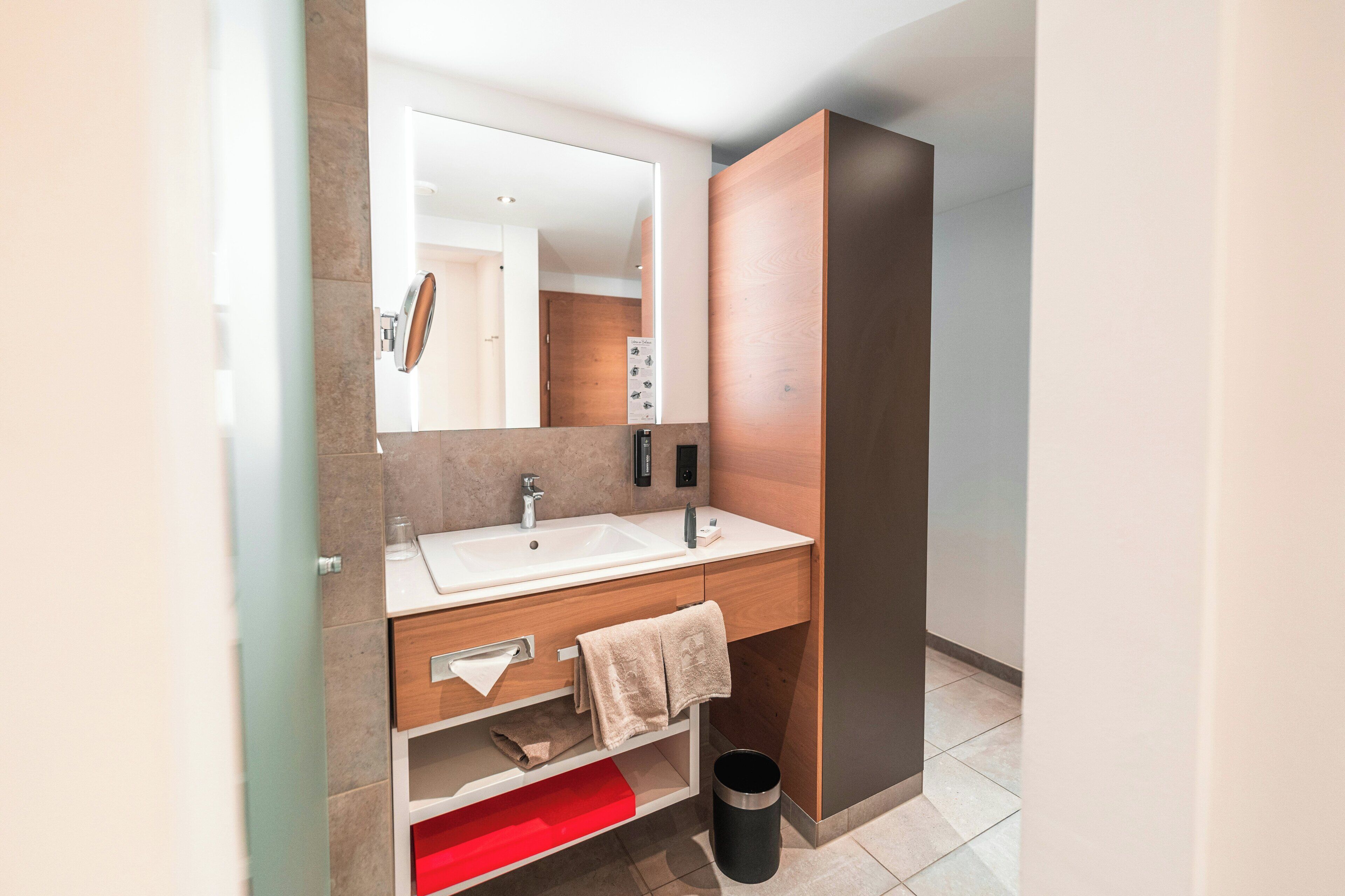 Une salle de bain moderne avec un lavabo blanc, un miroir et un meuble en bois.