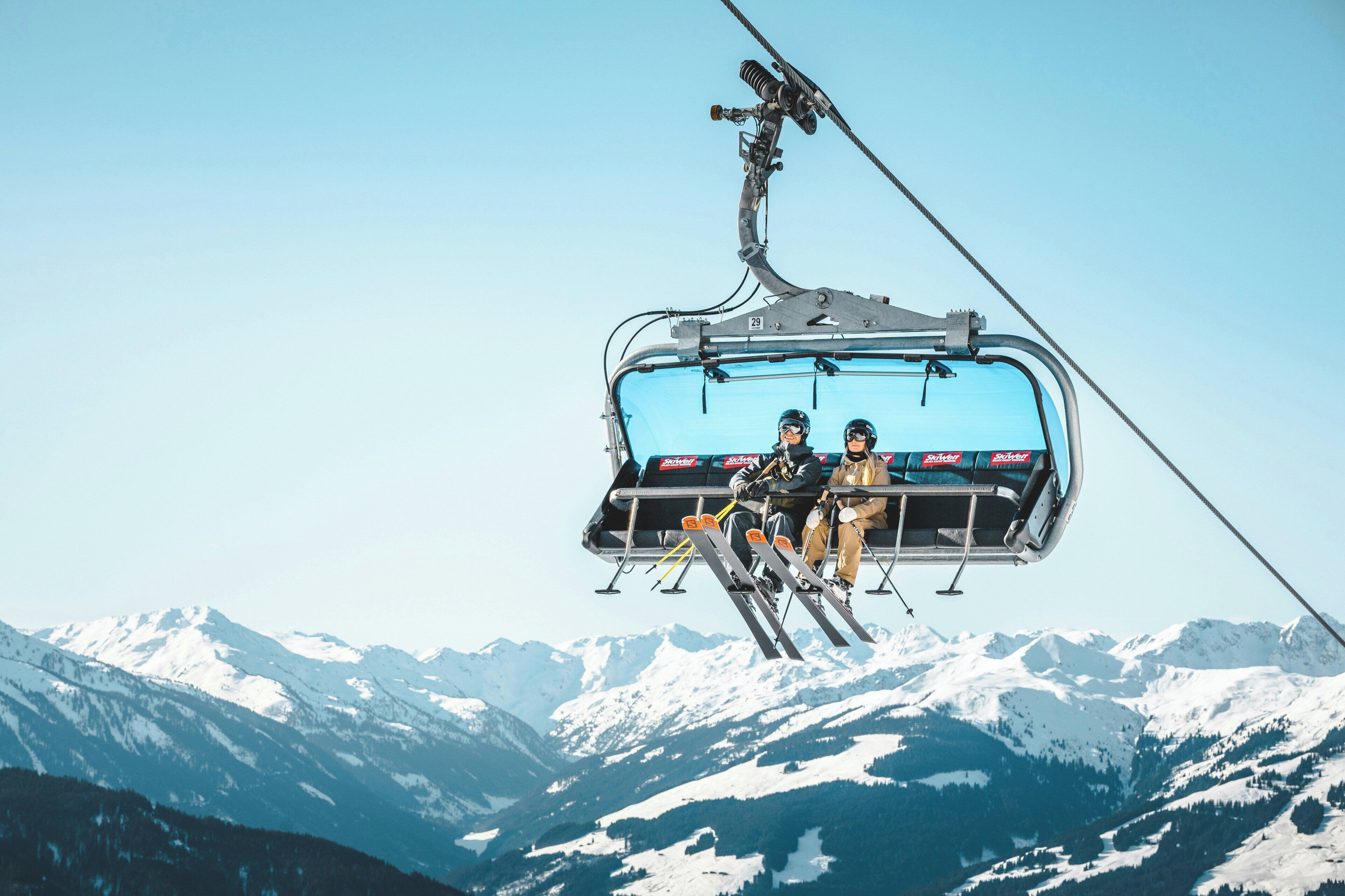 A ski lift with two passengers, a mountain landscape in the background.