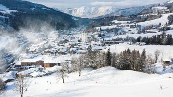 A snow-covered town with buildings, a church, and mountains in the background.
