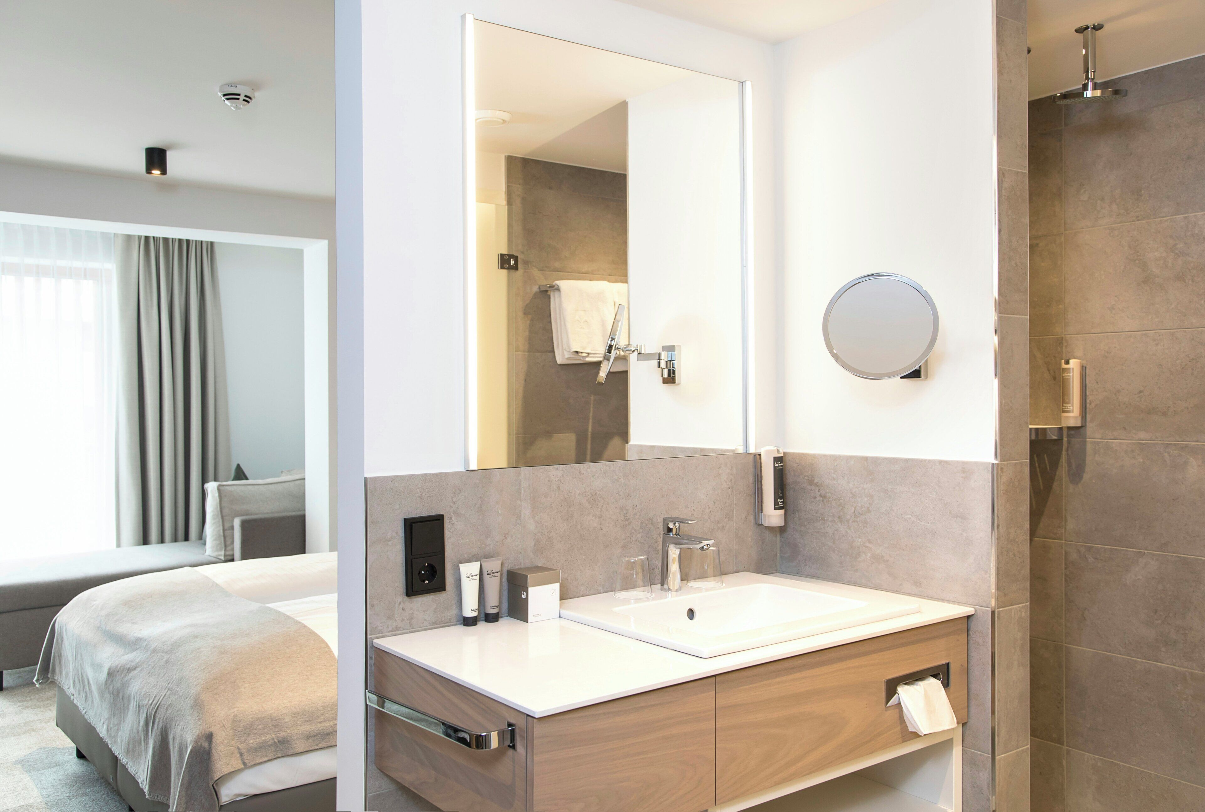Un baño moderno con un espejo grande, un lavabo y una ducha.