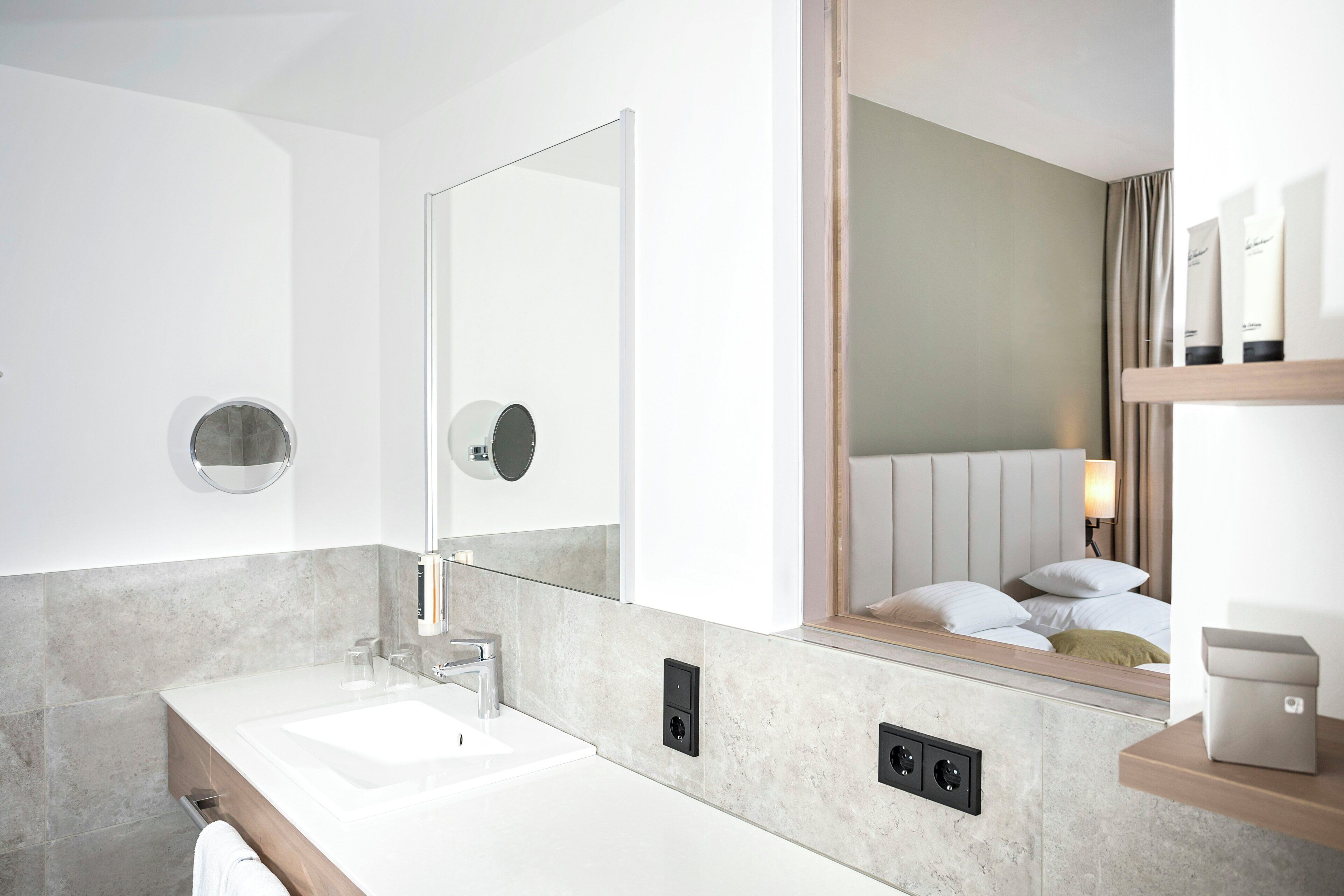 A modern bathroom with a large mirror, a sink, and a toilet.