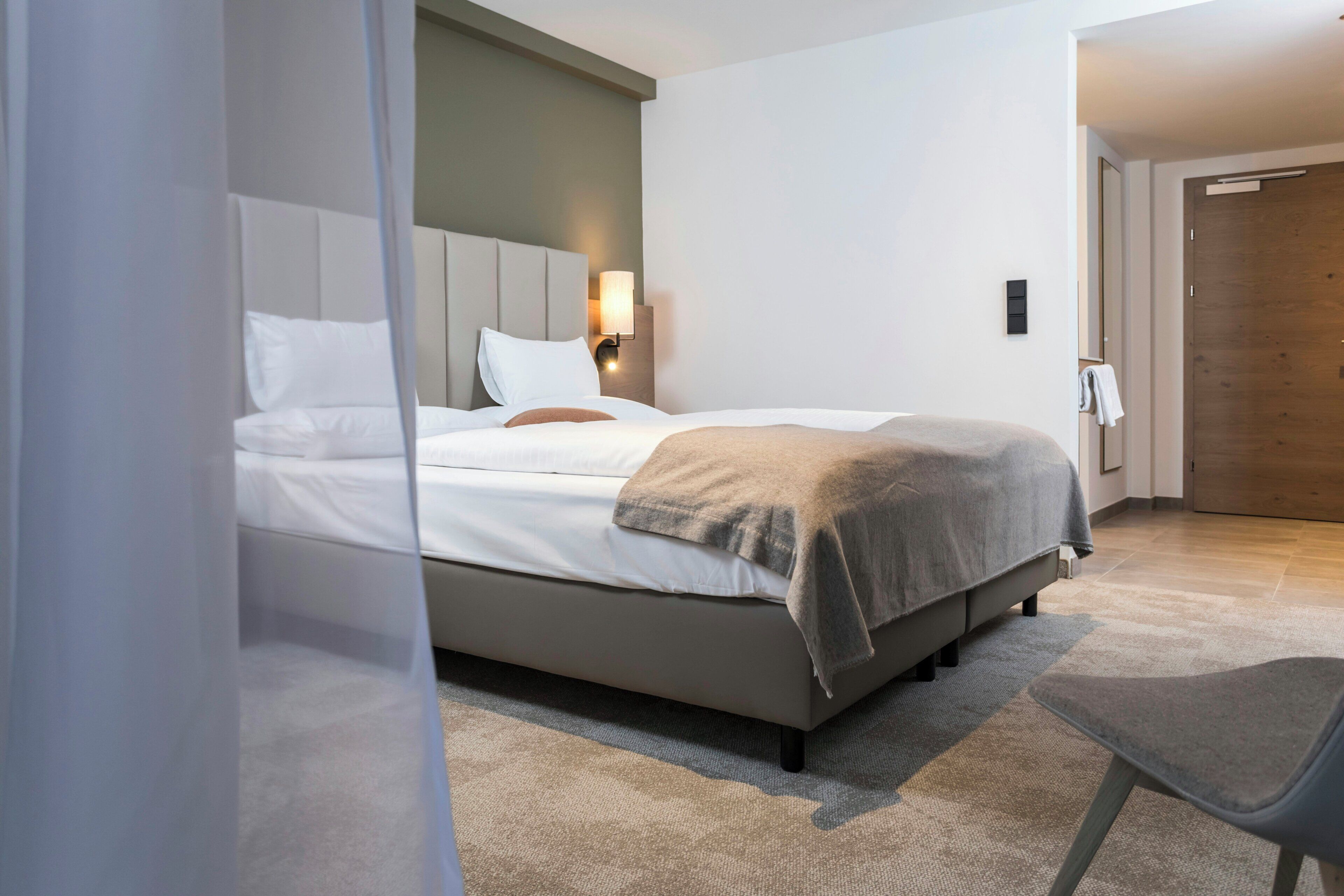 Une chambre d’hôtel moderne, équipée d’un lit, d’une table de chevet, d’une lampe et d’une chaise.