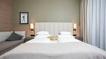 Une chambre d’hôtel avec un grand lit, deux tables de chevet avec des lampes, un canapé et un tableau accroché au mur.