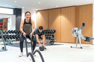 Un gimnasio con equipo de ejercicio, incluyendo una máquina de remo y pesas con mancuernas.