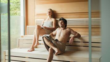 Two people sitting on a wooden bench with a wooden wall behind them.