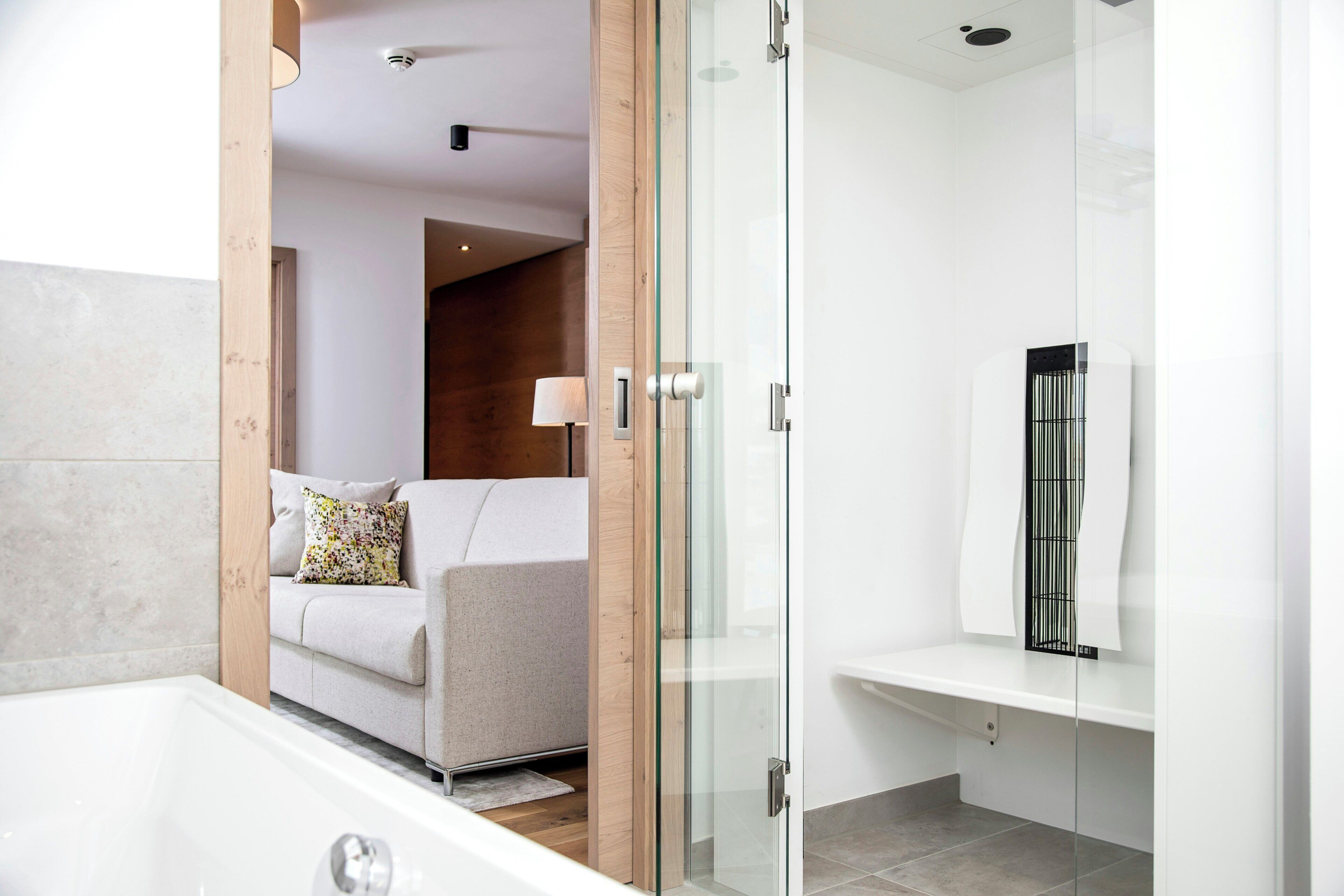 Un baño moderno con cabina de ducha de vidrio, bañera y banco empotrado.