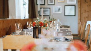 A dining table set with wine glasses, a vase with flowers, and cutlery.