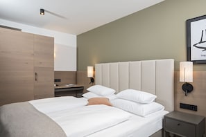Ein modernes Hotelzimmer mit einem großen Bett, Nachttischen, einem Kleiderschrank und einem an der Wand befestigten Kunstwerk.