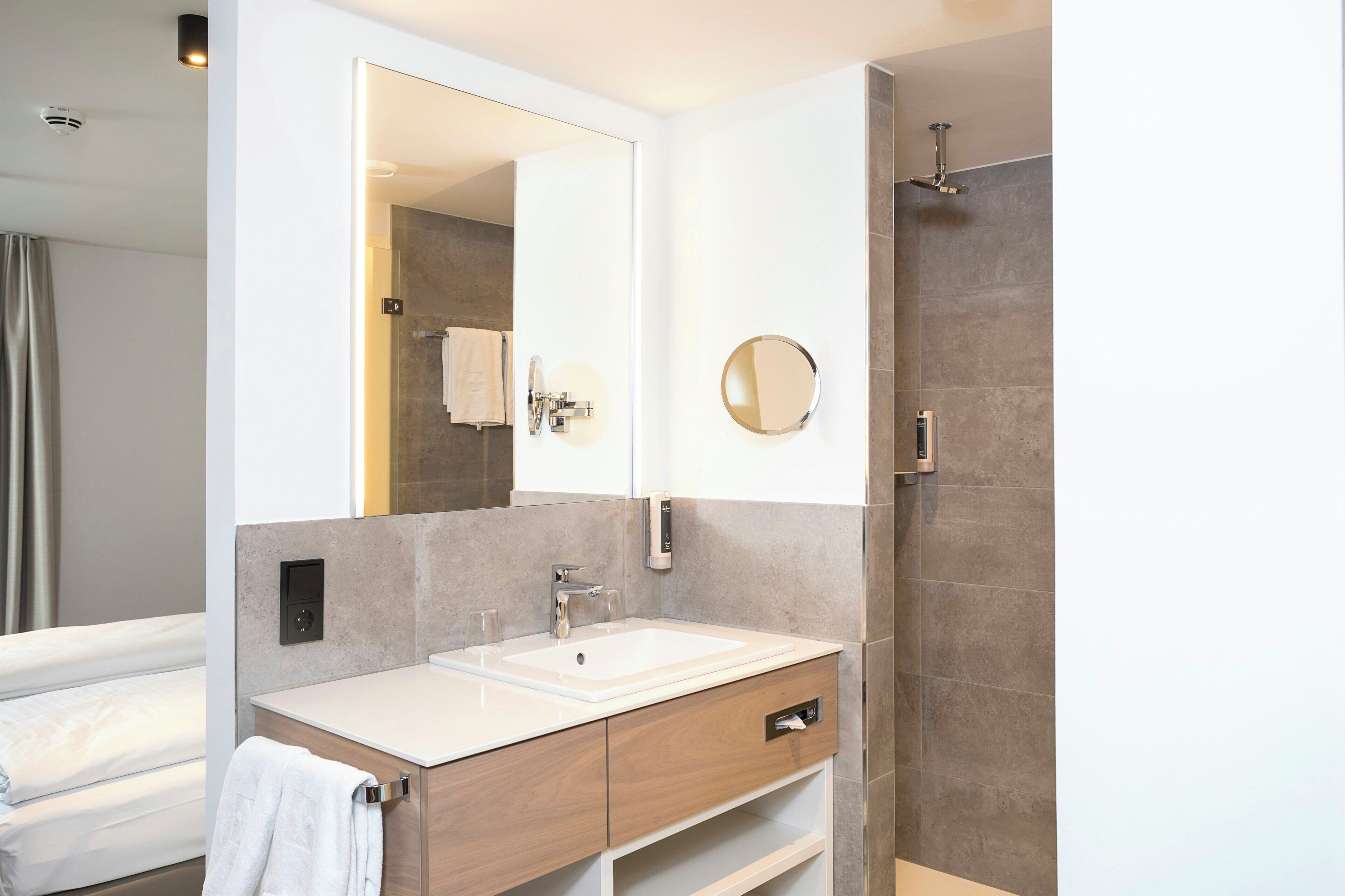 A modern bathroom with a large mirror, a sink, and a shower.