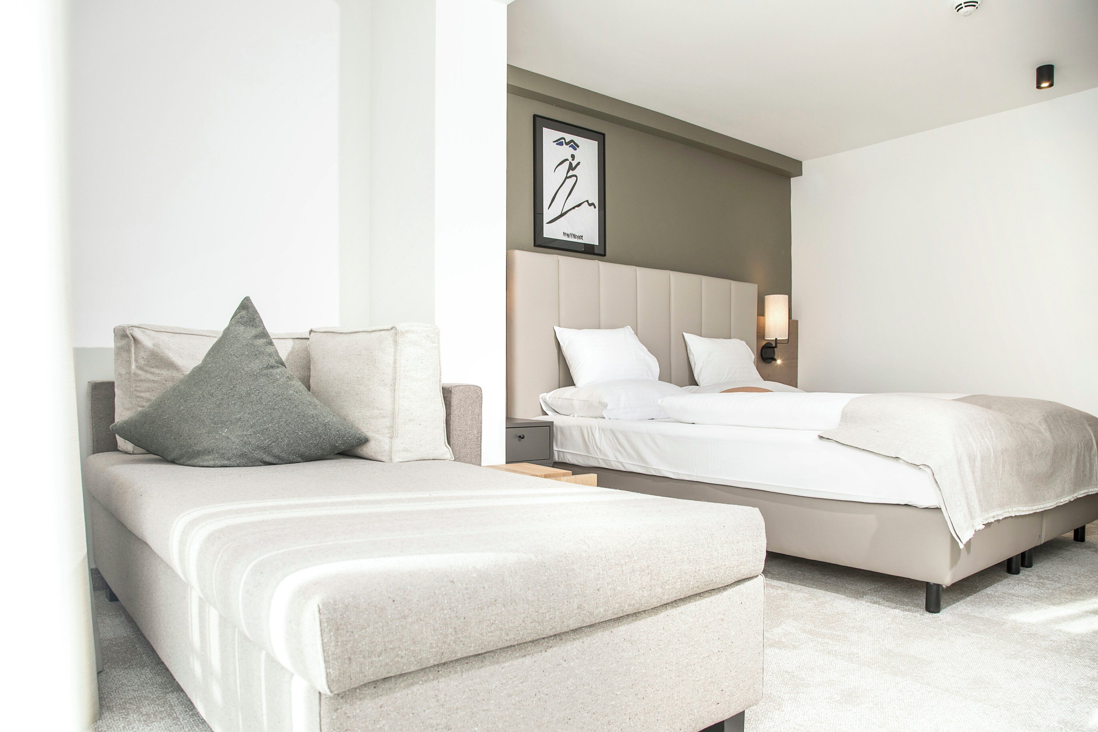 Quarto de hotel moderno com cama, mesa de cabeceira e uma obra de arte na parede.