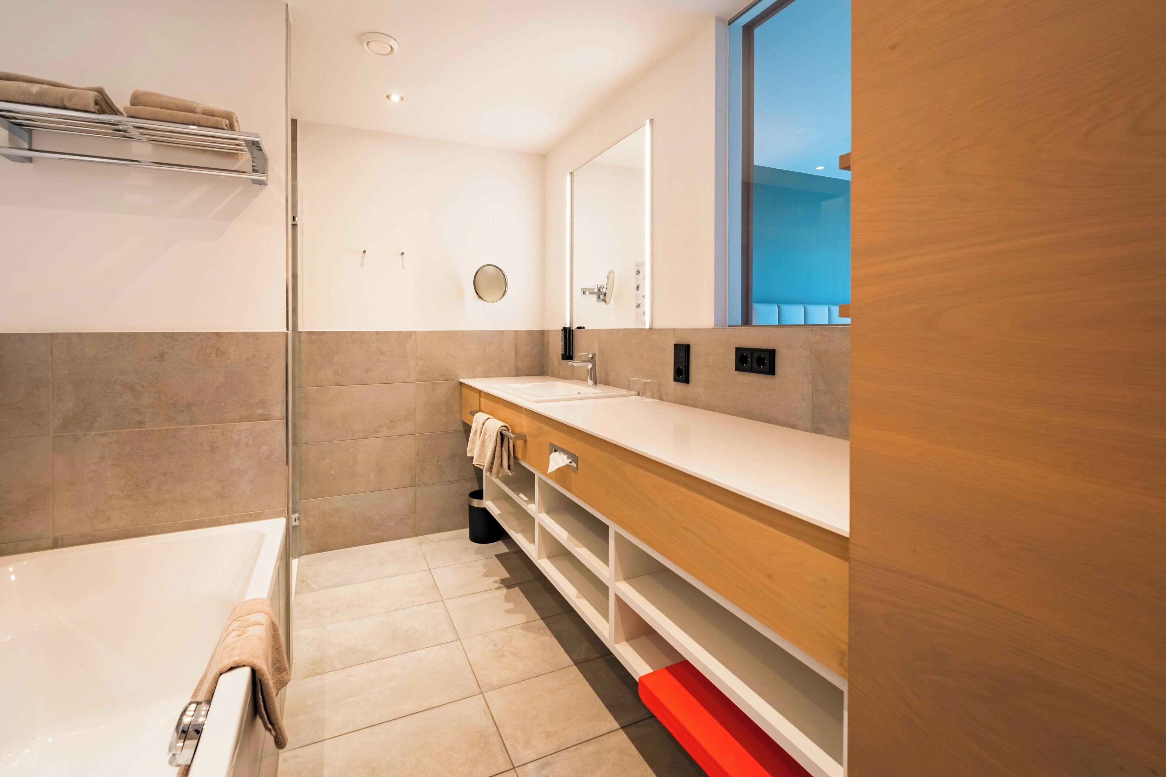 A modern bathroom with a bathtub, a vanity with a mirror, and a towel rack.