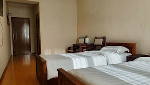 A hotel room with two single beds, a wooden floor, a small table with chairs, and a door leading to another room. - Land Hotel (Ulaanbaatar)