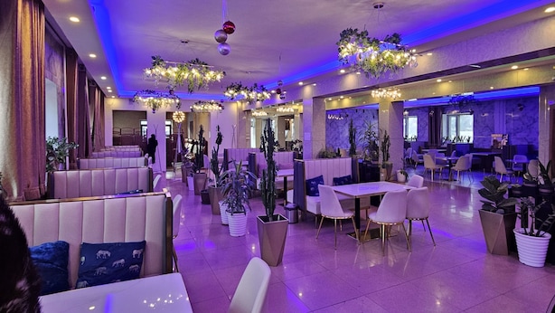 A spacious lobby with seating areas, tables, and potted plants. - Land Hotel (Ulaanbaatar)