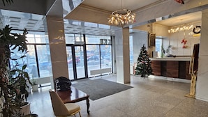 A spacious lobby with a reception desk, a Christmas tree, and a chair. - Land Hotel (Ulaanbaatar)
