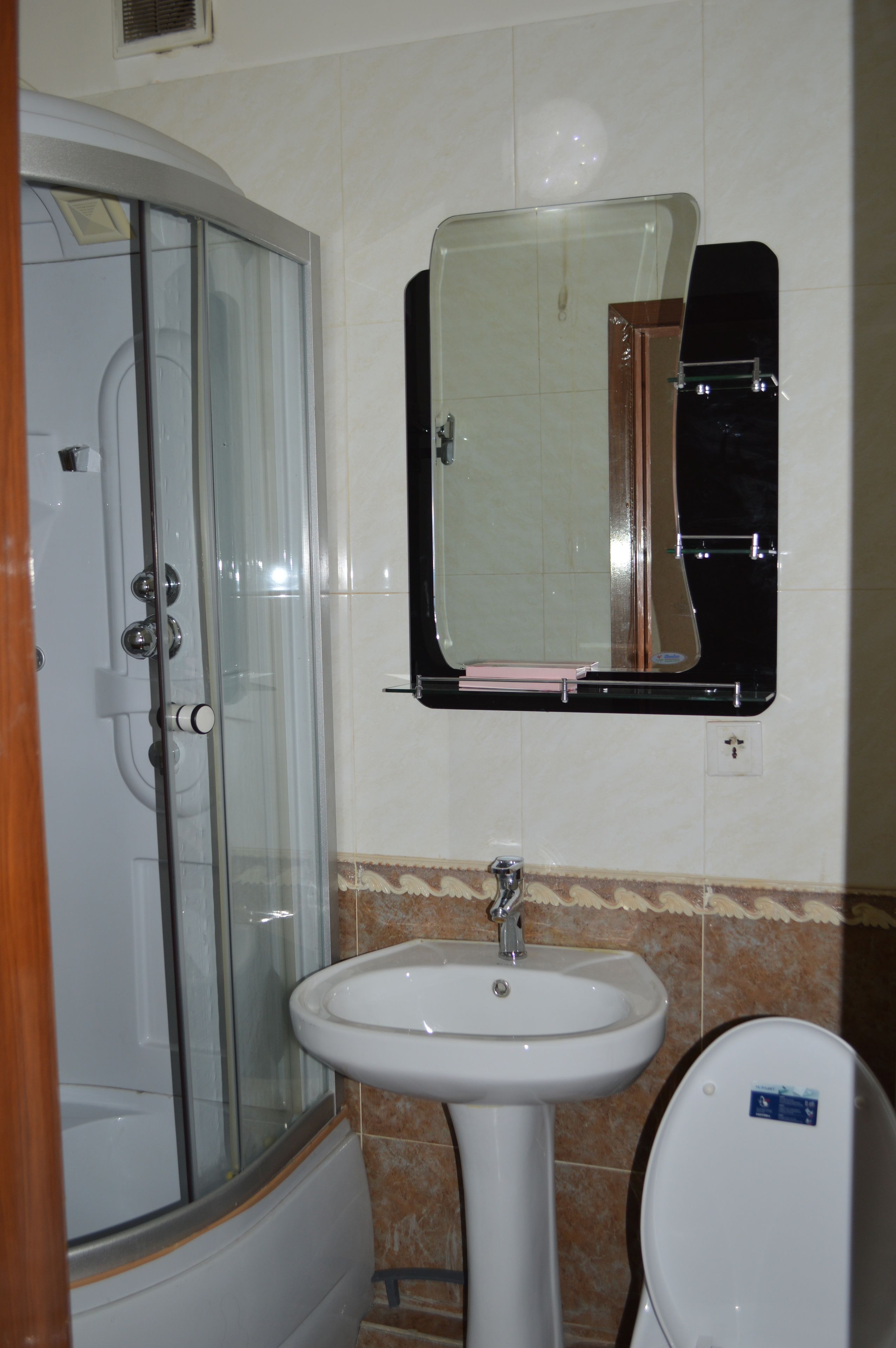 A bathroom with a glass shower enclosure, a white sink, and a mirror above the sink.
