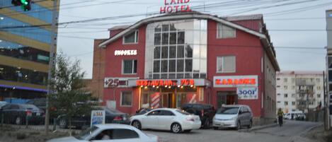 A building with a sign reading "LAND HOTEL" and "RESTAURANT PUB" on the ground floor.