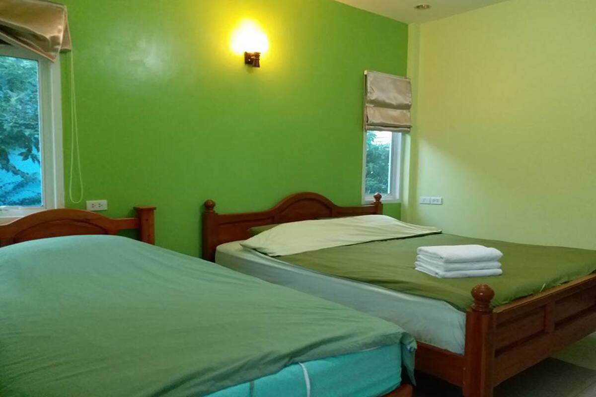 A room with two single beds, a window with a view of trees, and a wall-mounted light fixture.