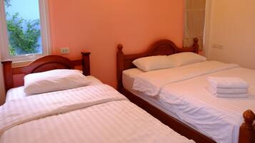 Une chambre avec deux lits simples, chacun doté de draps blancs et d’une tête de lit en bois.