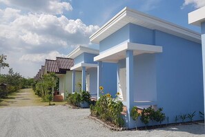 A row of blue buildings with white trim, each with a porch and steps leading to the entrance.