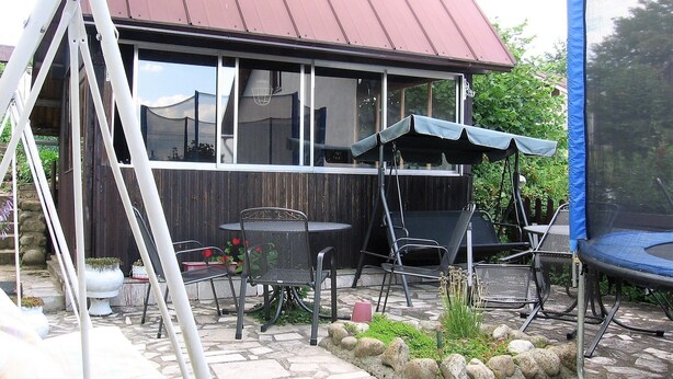 A patio area with a table and chairs, a swing set, and a trampoline. - Penzión Závada (Nova Lesna)