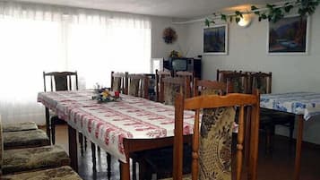 Un comedor con una mesa larga, sillas, un televisor y decoración en la pared.