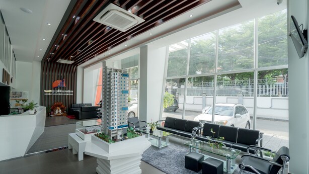 A modern hotel lobby with a reception desk, seating area, and large windows offering a view of the street. - Monorom Apartment Boeung Kang Keng 1 (Phnom Penh)