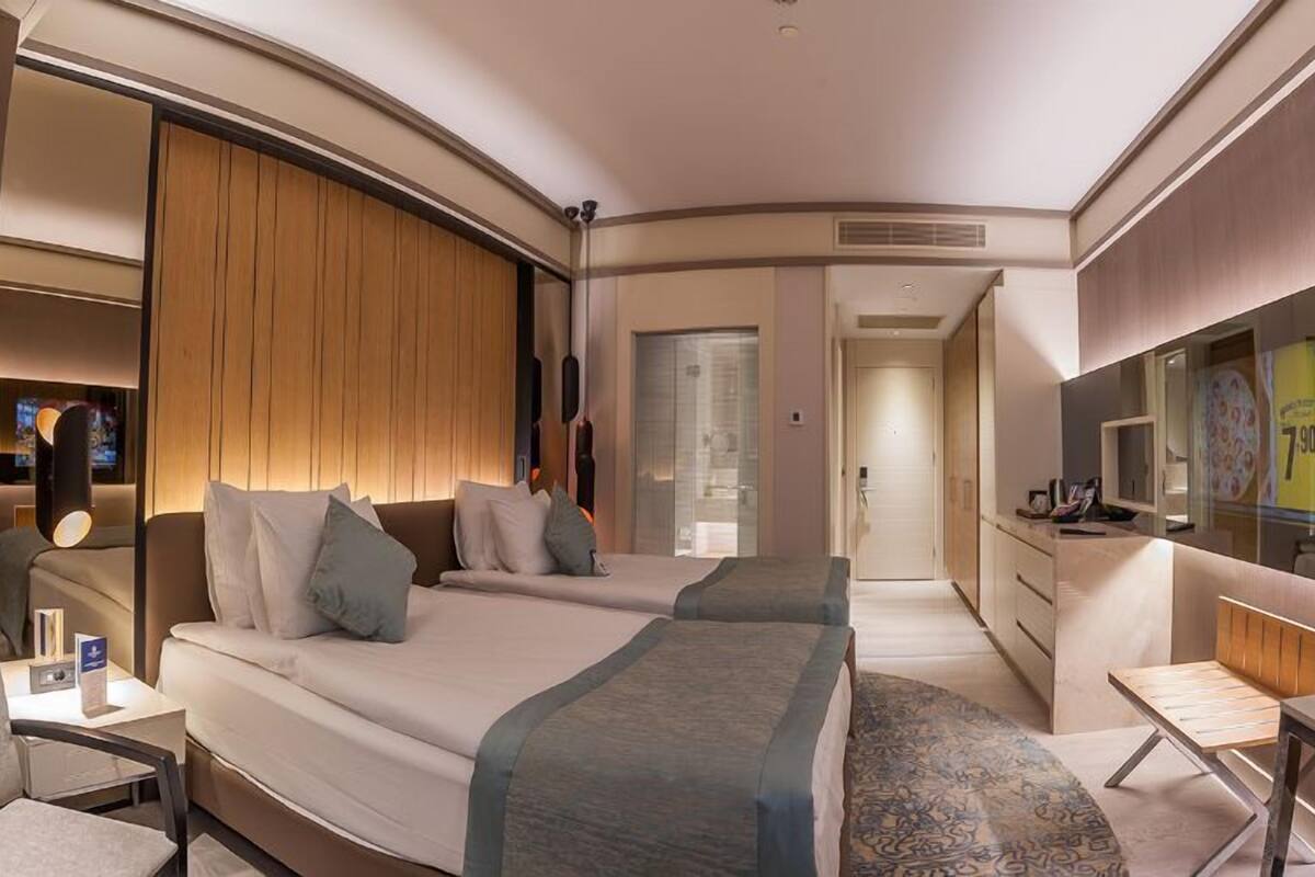 Une chambre d’hôtel comprenant un lit, des tables de chevet, un bureau, une chaise, une télévision et une armoire.