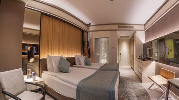 A modern hotel room with a large bed, a desk, a chair, and a bathroom visible through an open door.