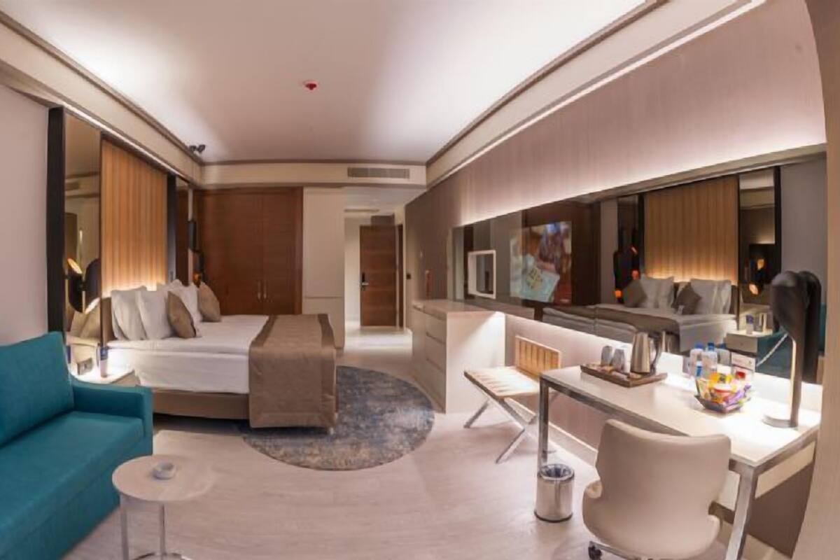 Une chambre d’hôtel avec un canapé, un lit, un bureau, une chaise et un miroir.