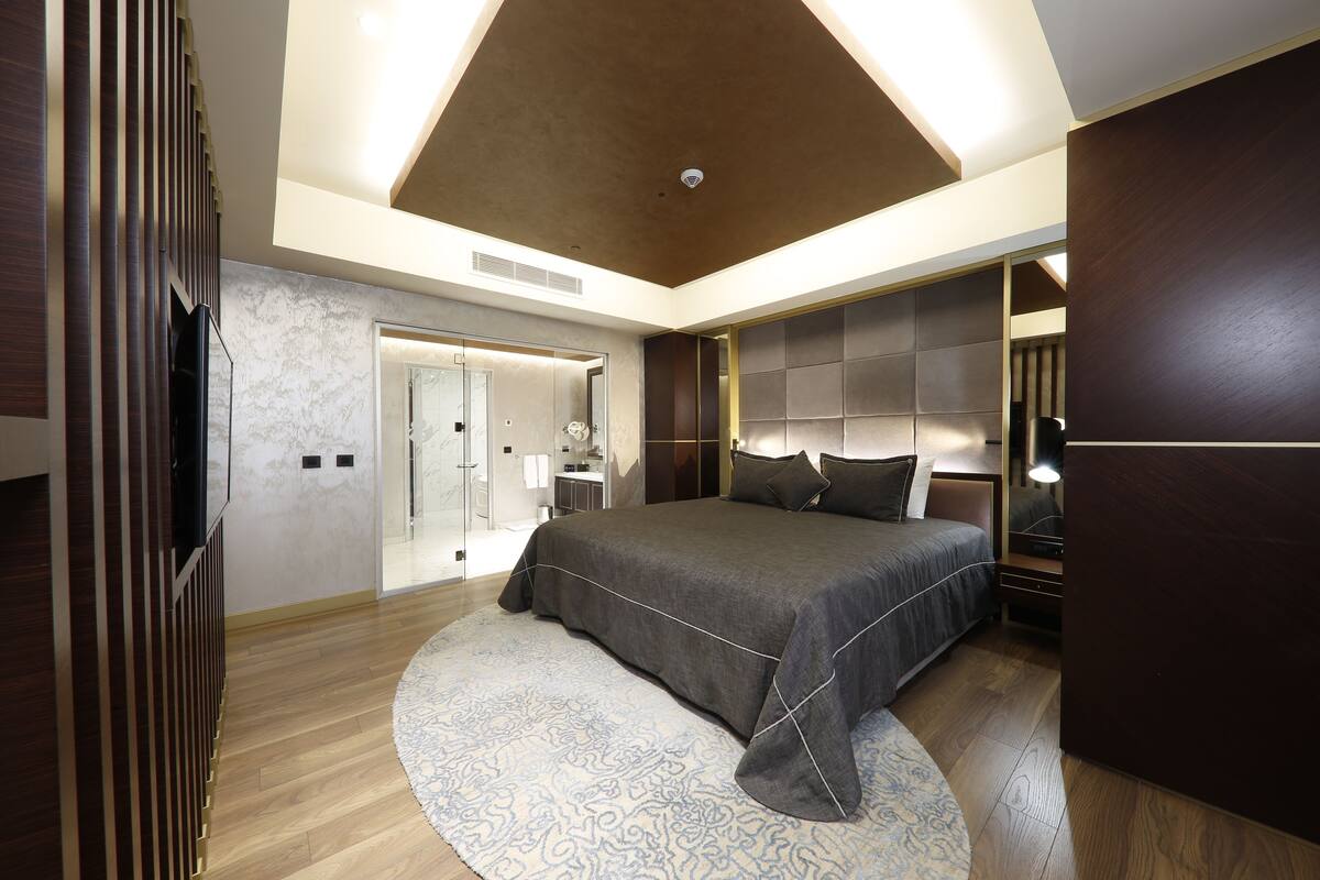 Une chambre moderne avec un grand lit, un dressing et une salle de bain dotée d’une porte en verre.
