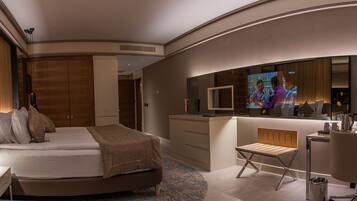 Una habitación de hotel moderna con cama, mesita de noche, escritorio, silla y televisor.