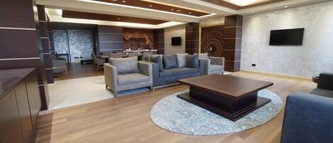 A modern living room with a sofa set, a coffee table, and a TV mounted on the wall.