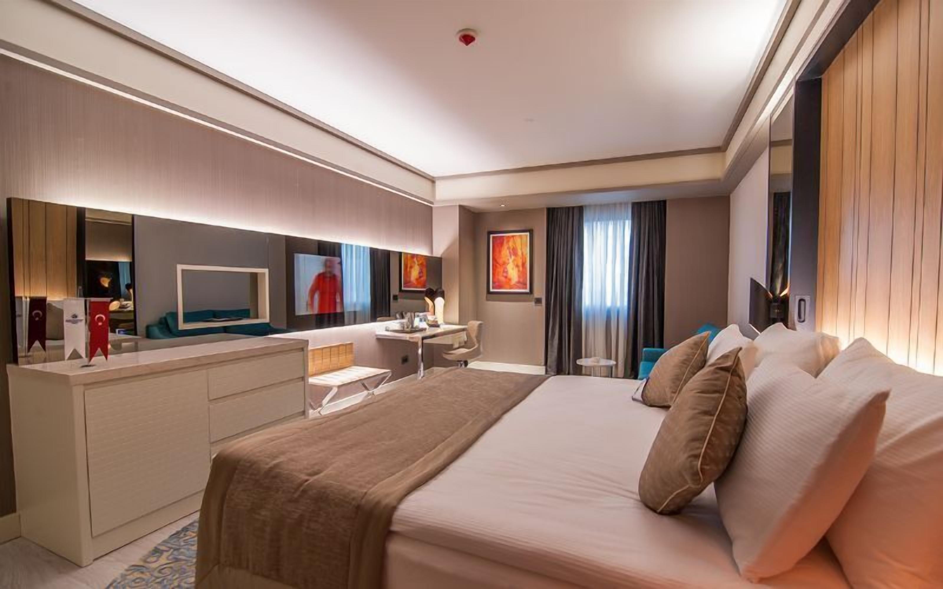 Una habitación de hotel moderna con una cama grande, un escritorio, un espejo y un televisor.
