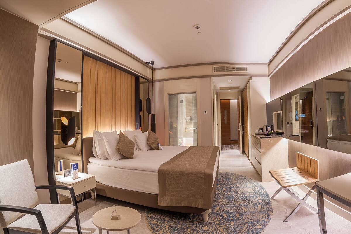 Une chambre d’hôtel comprenant un lit, un bureau, une chaise, une petite table et un miroir.