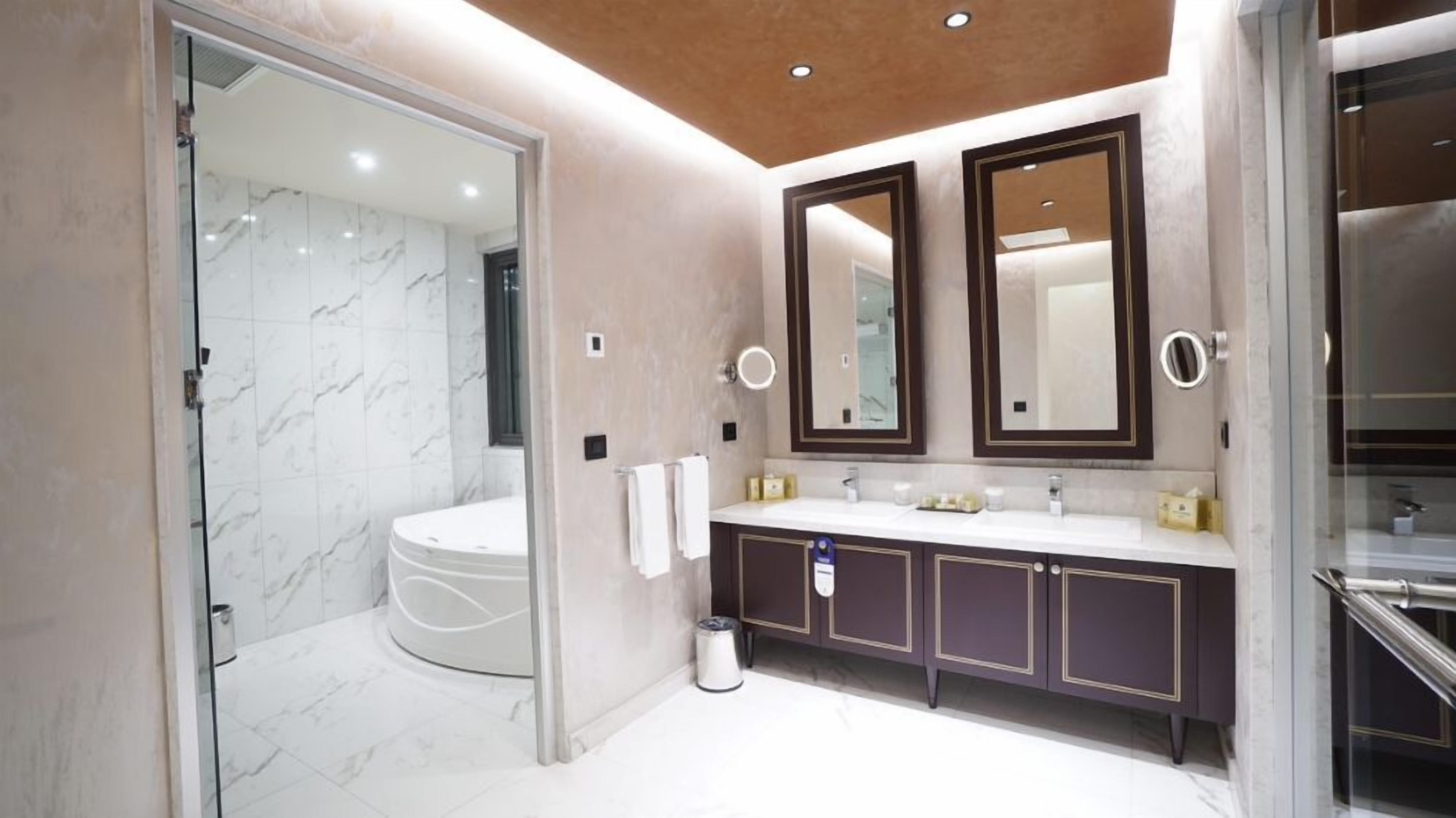 A modern bathroom with a glass-enclosed shower, a white toilet, and a vanity with two mirrors and a sink.