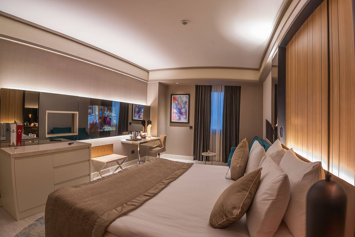 Une chambre d’hôtel moderne dotée d’un grand lit, d’un bureau, d’une coiffeuse et d’un grand miroir.