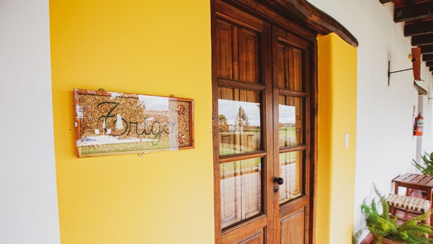 A wooden door with glass panels, a corkboard with a handwritten sign, and a potted plant on a tiled floor.