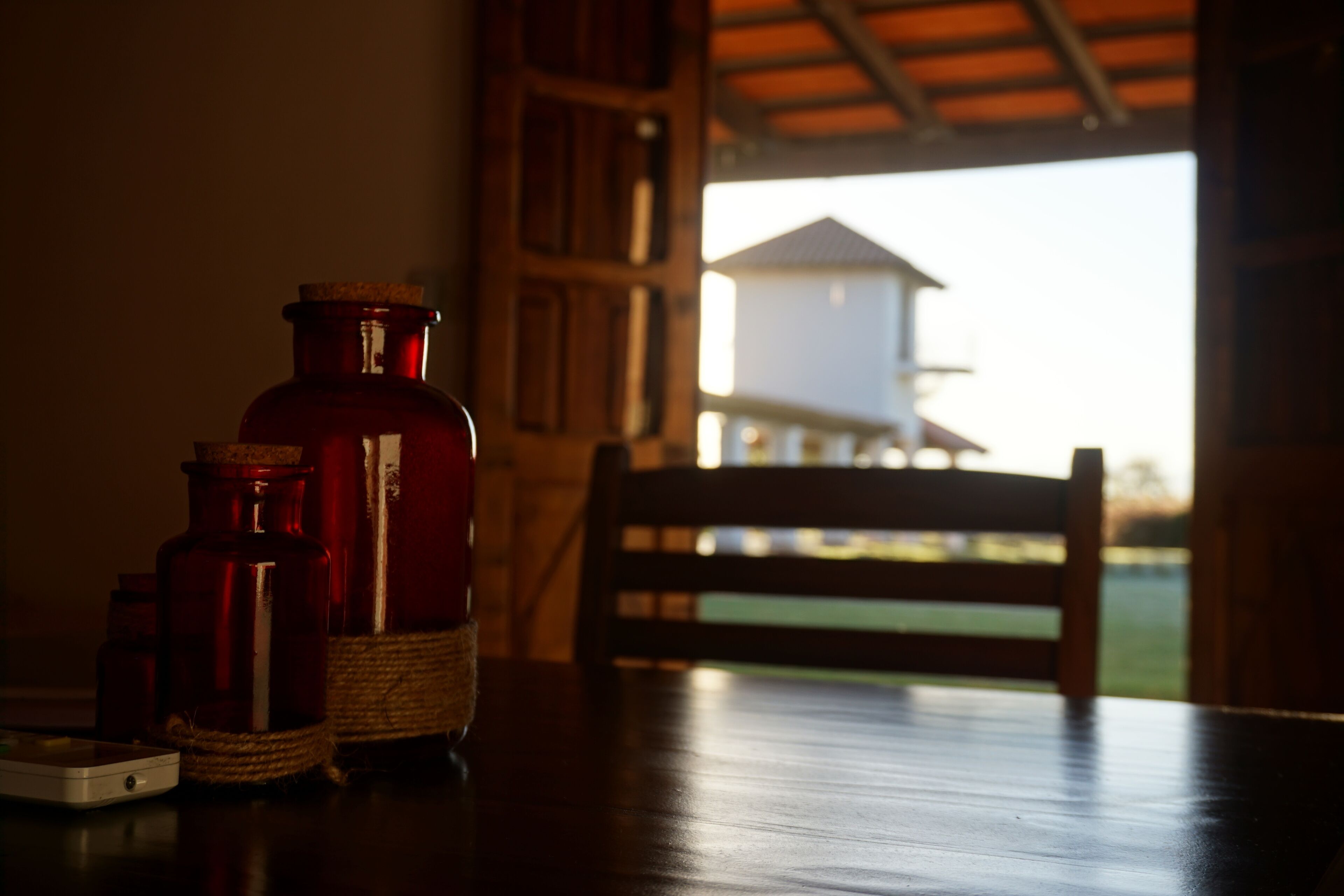 Una mesa de madera con una botella roja y un dispositivo blanco encima.