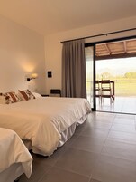A bedroom with a large bed, a table with chairs, and a view of the outdoors.