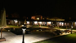 A nighttime outdoor area with a swimming pool, lounge chairs, and umbrellas. - Finca Las Margaritas (Chicoana)
