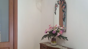 A wooden console table with a vase of flowers and a mirror with a floral design. - B&B Rosa Dei Venti (Orvieto)