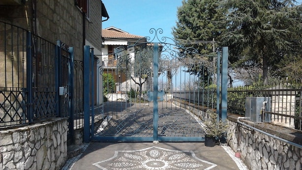 A gated entrance with a decorative pavement design, stone walls, and a metal gate. - B&B Rosa Dei Venti (Orvieto)
