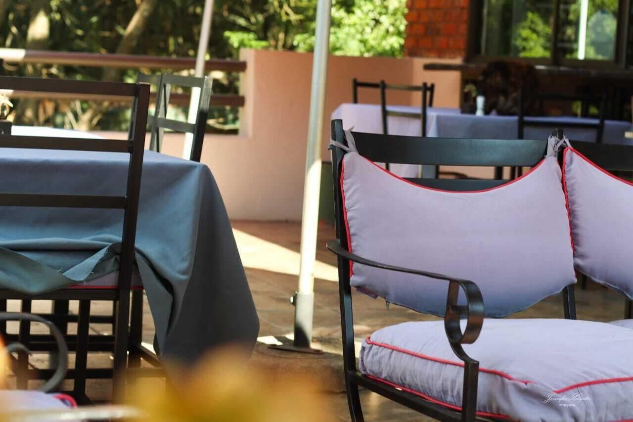 Outdoor seating with tables and chairs, some covered with tablecloths.
