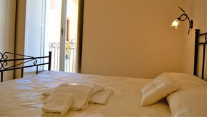 A neatly made bed with folded towels and pillows, a black metal headboard, and a wall-mounted light fixture. - B&B THE TOWER Tropea (Tropea)