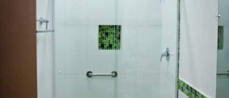 A bathroom with a glass-enclosed shower, a toilet, and a sink with a mirror above it.