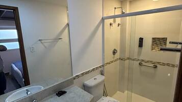 A bathroom with a glass-enclosed shower, a double sink vanity, and a toilet.