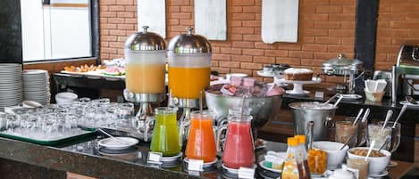 A buffet with various food and drink options, including a fruit bar and a selection of juices.