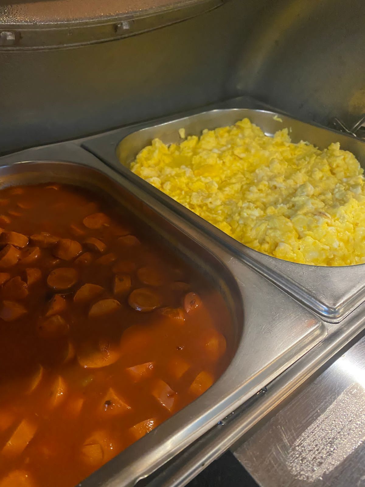 A buffet with two dishes: a red soup with vegetables and a tray of scrambled eggs.
