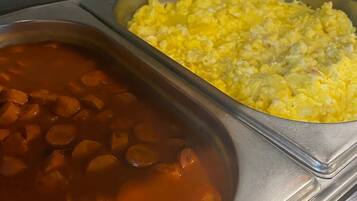 A buffet with two dishes: a red soup with vegetables and a tray of scrambled eggs.